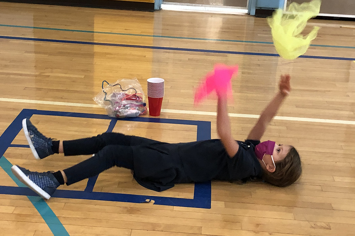 Girl lying on the floor playing with scarves 