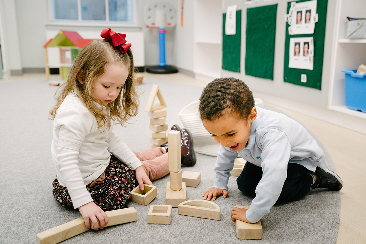 Girl and boy sit on the floor playing with blocks