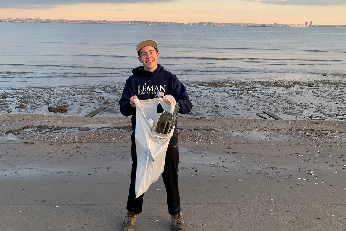 Teenager standing on the beach holding a garbage bag 